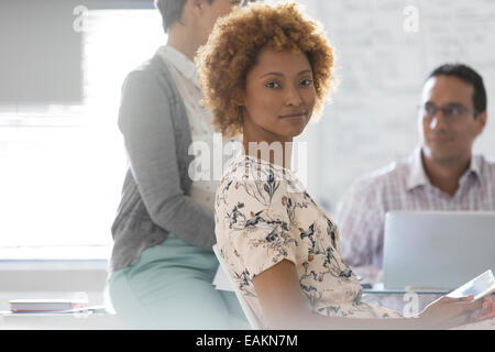 Portrait of businesswoman in office, colleagues in background Stock Photo