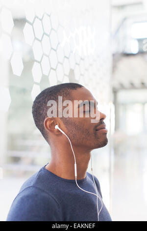 Portrait of young businessman listening to music on earphones Stock Photo