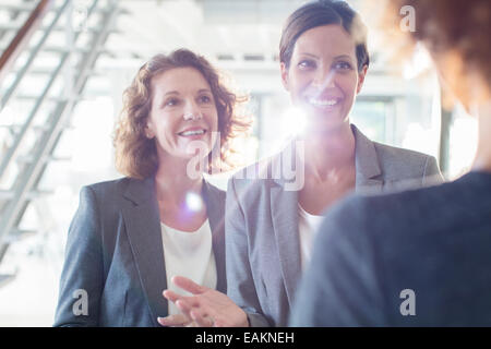 Three smiling businesswomen talking in office corridor Stock Photo