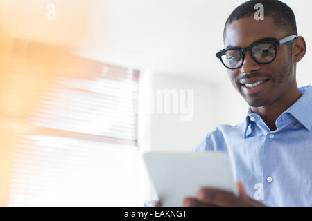 Portrait of young businessman wearing glasses using digital tablet in office Stock Photo