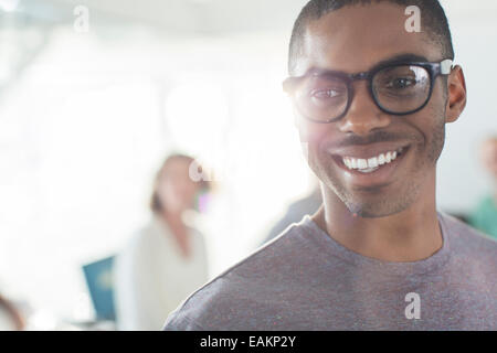 Portrait of young smiling man wearing glasses, woman in background Stock Photo