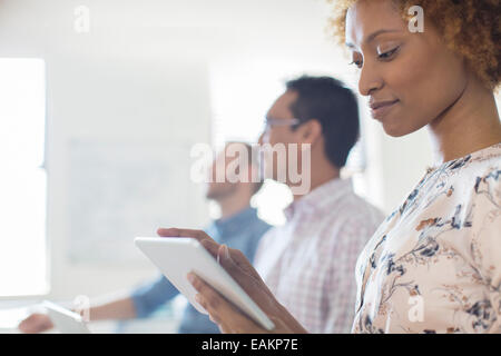 Portrait of woman using tablet in office, colleagues in background Stock Photo