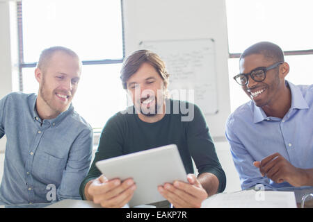 Three smiling men working with digital tablet in office Stock Photo