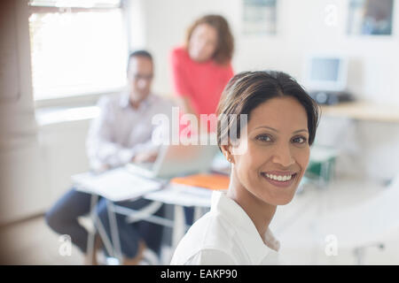 Portrait of smiling businesswoman in office, colleagues working in background Stock Photo