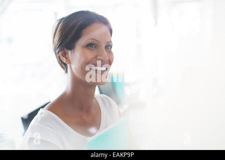 Portrait of smiling woman holding documents in office Stock Photo