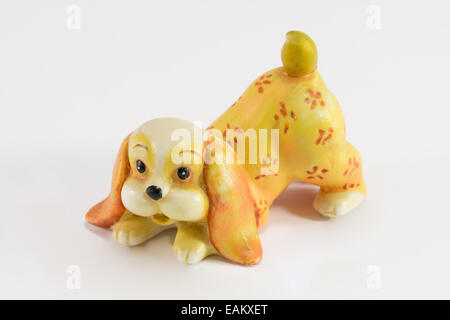 Statuette of dog sitting on white background, ceramic dog figurine Stock Photo
