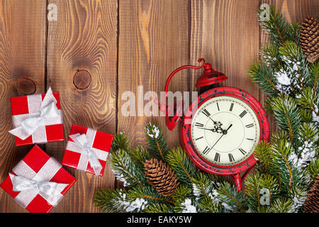Christmas clock over wooden background with snow fir tree and gift boxes. View from above with copy space Stock Photo