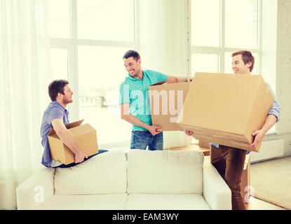 smiling male friends carrying boxes at new place Stock Photo