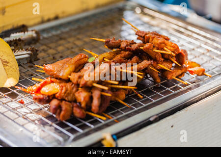 cooking meat skewers on the grill in a thai food street market in bangkok Stock Photo