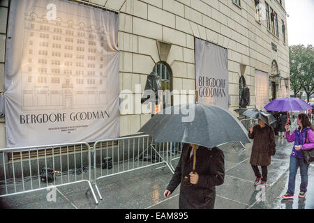 New York, USA. 17th November, 2014; in pouring rain passers by peek from under umbrellas at veiled Bergdorf Goodman Christmas windows awaiting grand unveiling at 6 p.m. Credit:  Dorothy Alexander/Alamy Live News Stock Photo