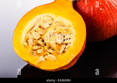 Half Red kuri squash, a small japanese  pumpkin with reflection over a glass background Stock Photo