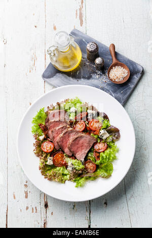 Salad leaves with sliced roast beef and sun-dried cherry tomatoes on white plate Stock Photo
