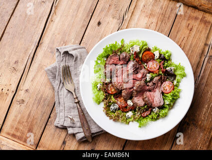 Salad leaves with sliced roast beef and sun-dried cherry tomatoes on wooden background Stock Photo