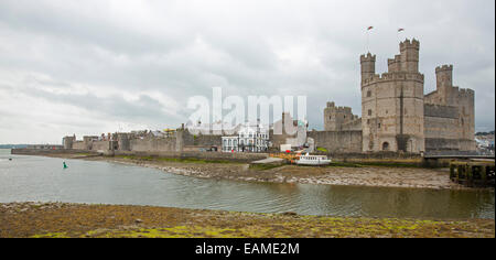 Panoramic view of spectacular Caernarfon castle towering over River Seiont with immense towers spearing into stormy sky in Wales Stock Photo
