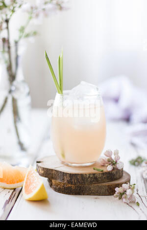 Pink Grapefruit Cocktail with Lemongrass and Flowers on White Wood Stock Photo