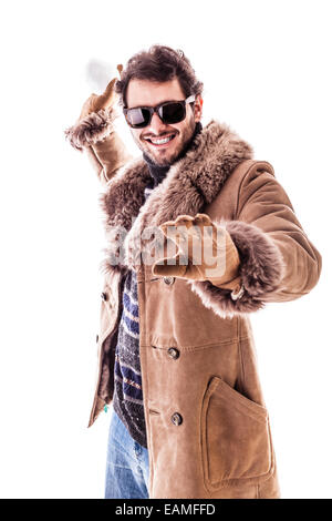 a young man wearing a sheepskin coat isolated over a white background playing with a snowball Stock Photo