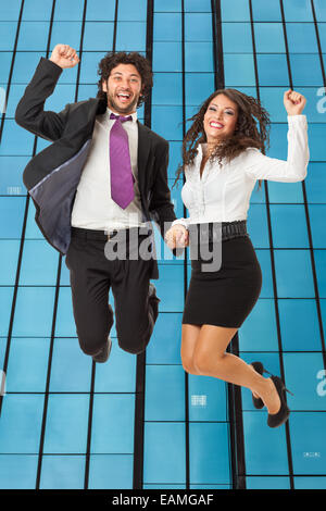 An handsome businessman and a gorgeous businesswoman jumping over a skyscraper Stock Photo