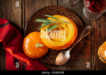 Pumpkin soup in a small pumpkin with leaf of sage Stock Photo