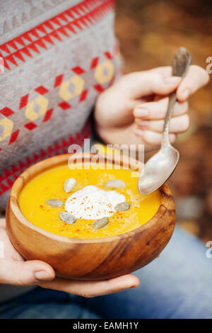 Woman holding pumpkin soup in a rustic bowl outside Stock Photo