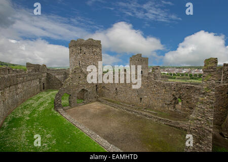 View from high stone wall of vast inner section & towers of ruined 13th century Kidwelly castle with town in distance in Wales Stock Photo