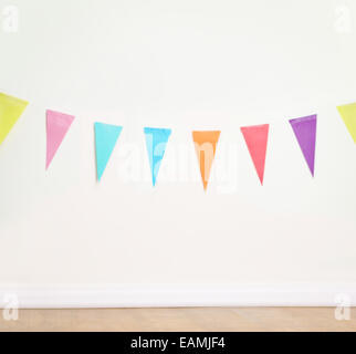 Birthday decoration flags on a plain white wall shot with tilt and shift lens Stock Photo