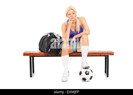 Worried female football player sitting on a bench isolated on white background Stock Photo