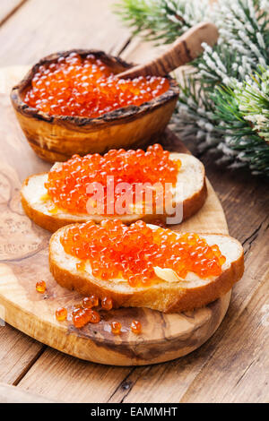 Sandwiches with Salmon red caviar and green Fir Christmas branch on wooden background Stock Photo
