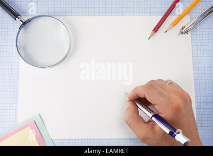 male hand writing by pen and magnifying glass on graph grid paper Stock Photo