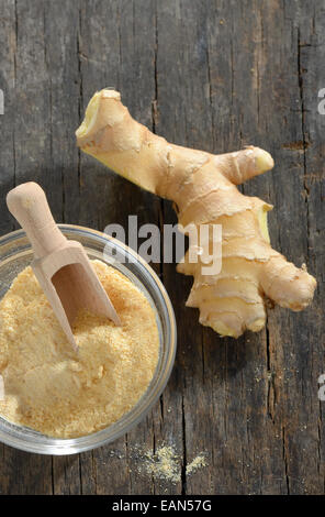 Fresh ginger root with a spicy powder in bowl, wooden background Stock Photo