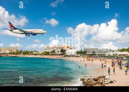 A jet approaches Princess Juliana Airport above onlookers on Maho Beach on Sint Maarten. Stock Photo