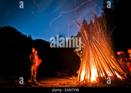 Two people sitting in front of a big campfire, by the night. Stock Photo