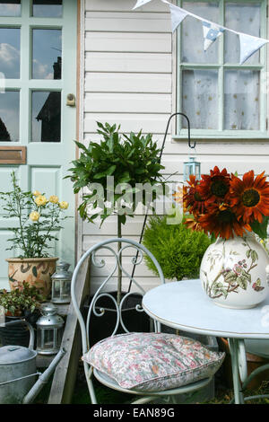 table with jug of sunflowers outside pretty clapboard house or shed Stock Photo