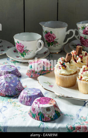 cakes and tea set on table cloth with paper cupcake cases Stock Photo