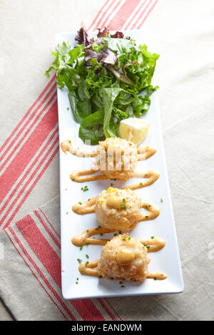 Lobster and shrimp fritters with green salad on a white plate Stock Photo