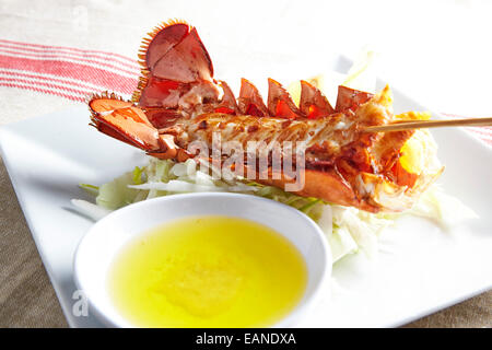 Main Lobster Tail skewered in the shell flash fried withe lemon butter and lemons and lettuce Stock Photo