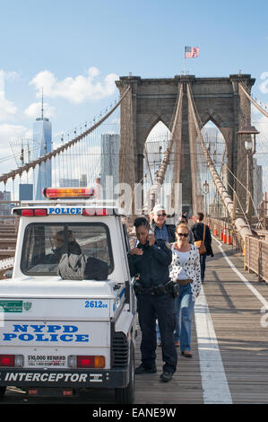 Female police officer using phone on Brooklyn Bridge, Manhattan, New York, USA Stock Photo