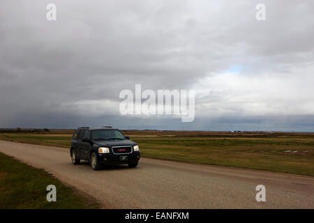 car driving on rural road as storm snow clouds forming over the prairies assiniboia Saskatchewan Canada Stock Photo