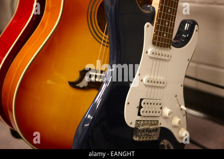 electric and acoustic guitars on a rack in a music training room Stock Photo