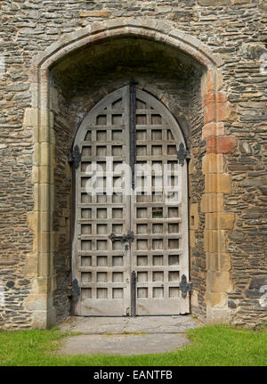 High old double doors with lattice pattern in arched stone alcove in walls of ancient ruins of  Valle Crusis abbey, Wales Stock Photo