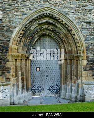 Old wooden door with huge decorative hinges surrounded by series of stone arches at ancient ruins of  Valle Crusis abbey, Wales Stock Photo