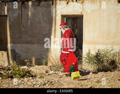 A fed up  Santa trudging along with his sack Stock Photo
