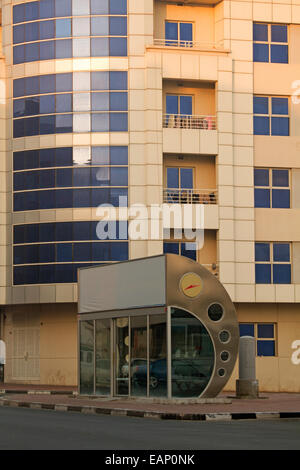 Unique air conditioned public bus stop shelter of dark glass & curved stainless steel beside apartment block in city of Dubai UAE Stock Photo