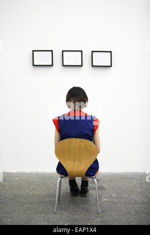 An artist sitting on a chair, looking at an artwork. Stock Photo