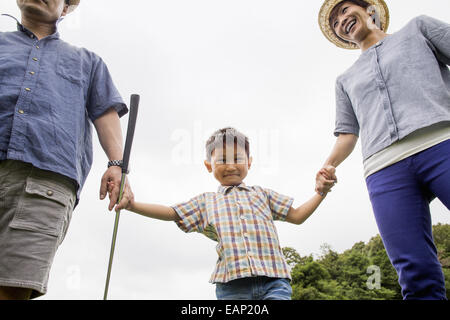 Family on a golf course. Two parents and a boy holding hands. Stock Photo