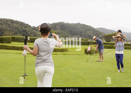 Family on a golf course.A child and three adults. a woman with a camera. Stock Photo