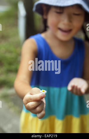 Young girl wearing a summer dress, holding a flower.