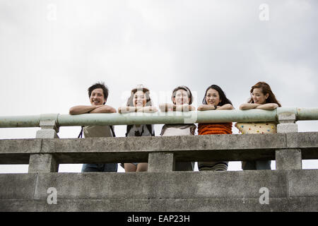 Friends in the park leaning on a parapet. View from below. Stock Photo