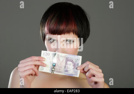 Young woman holding 20 pounds sterling banknote Stock Photo
