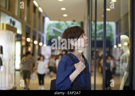 A woman in a shopping mall looking at a shop window display. Stock Photo