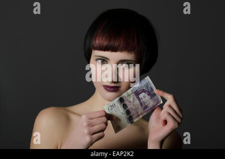 Young woman holding 20 pounds sterling banknote Stock Photo